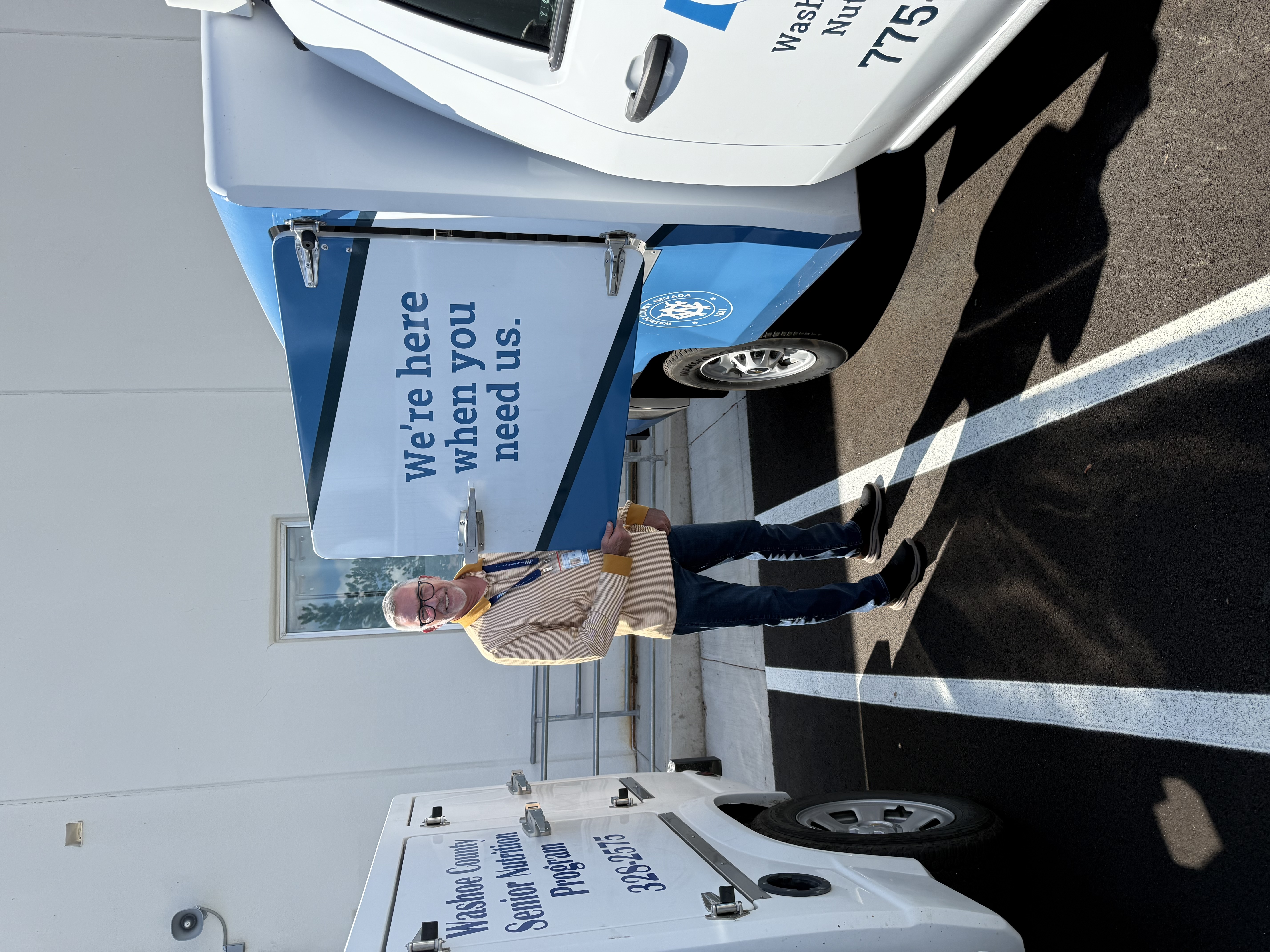 Image of a worker standing next to a meal delivery truck